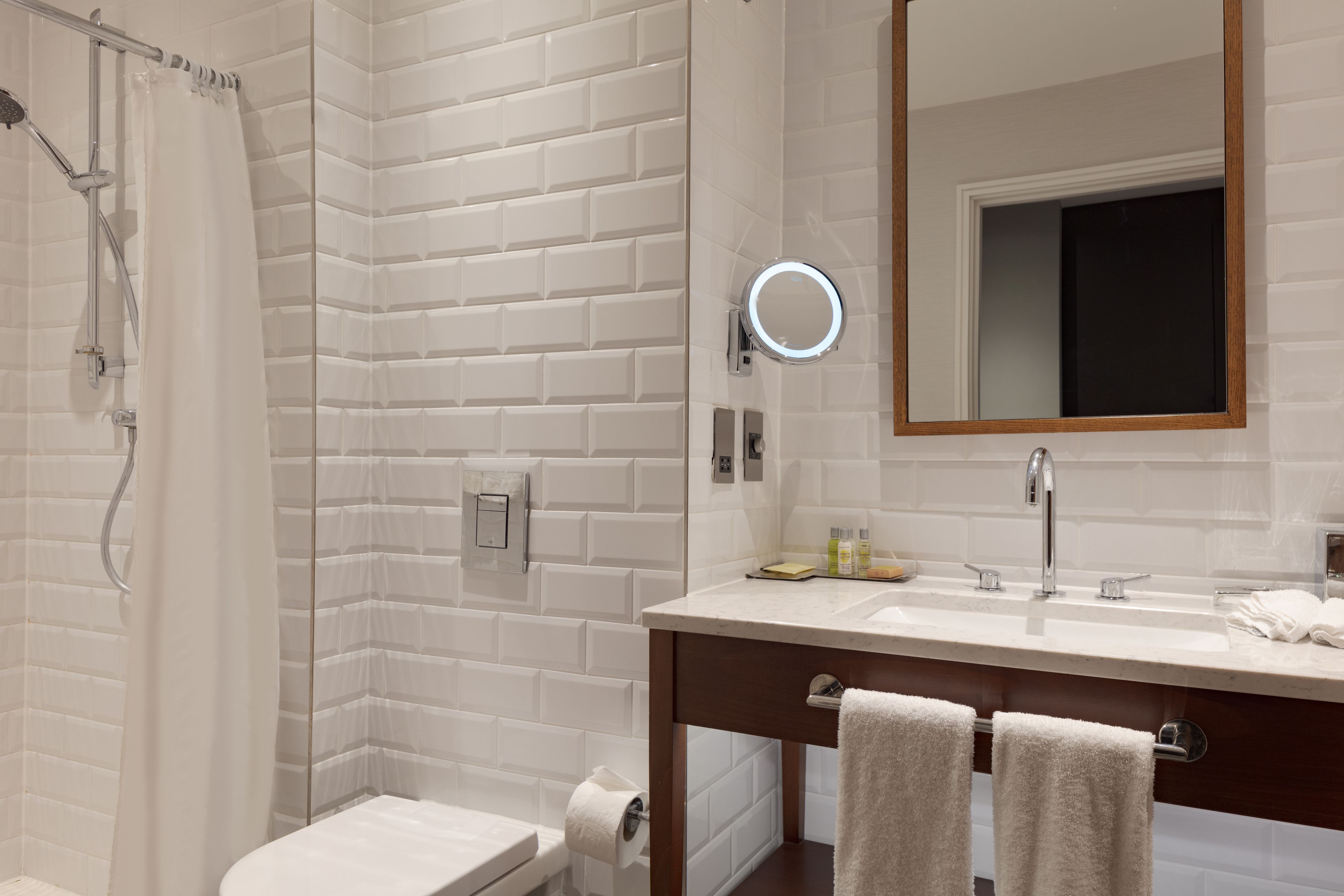A bathroom with a shower, toilet, and sink with a mirror.