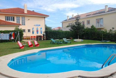 Una piscina al aire libre, sillones reclinables de piscina