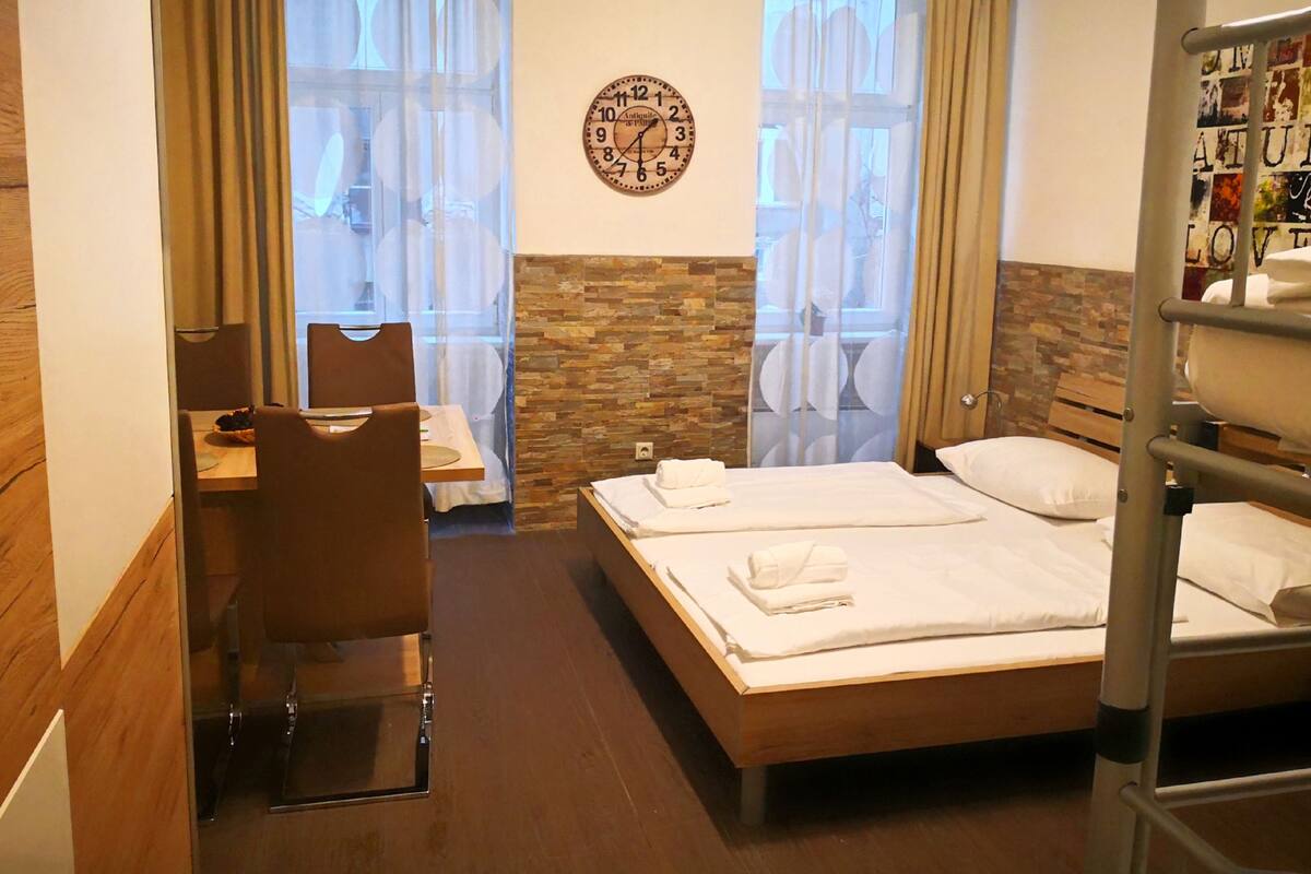 Habitación de hotel con cama de madera, un escritorio, una silla y una ventana con cortinas.