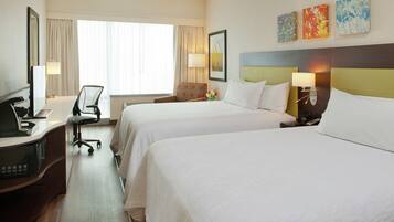 Une chambre d’hôtel avec deux lits, un bureau avec un ordinateur, une chaise et un téléviseur.