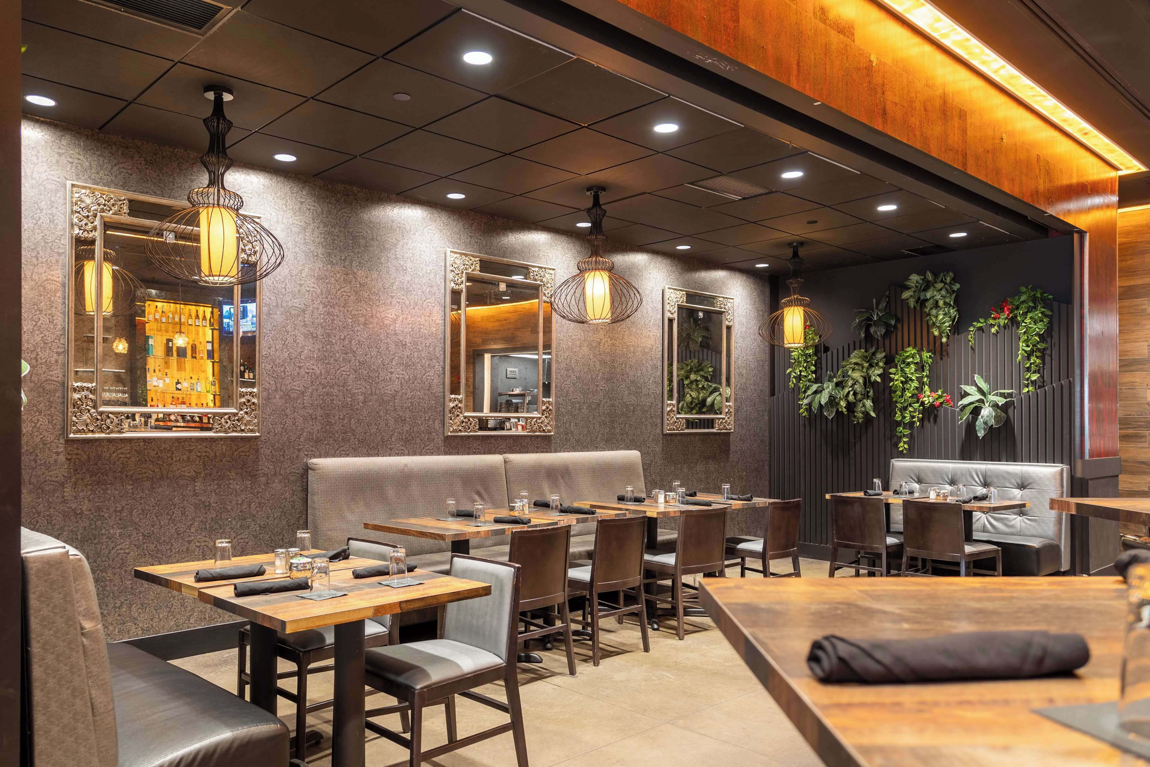 A restaurant interior with booths, tables, and hanging pendant lights.