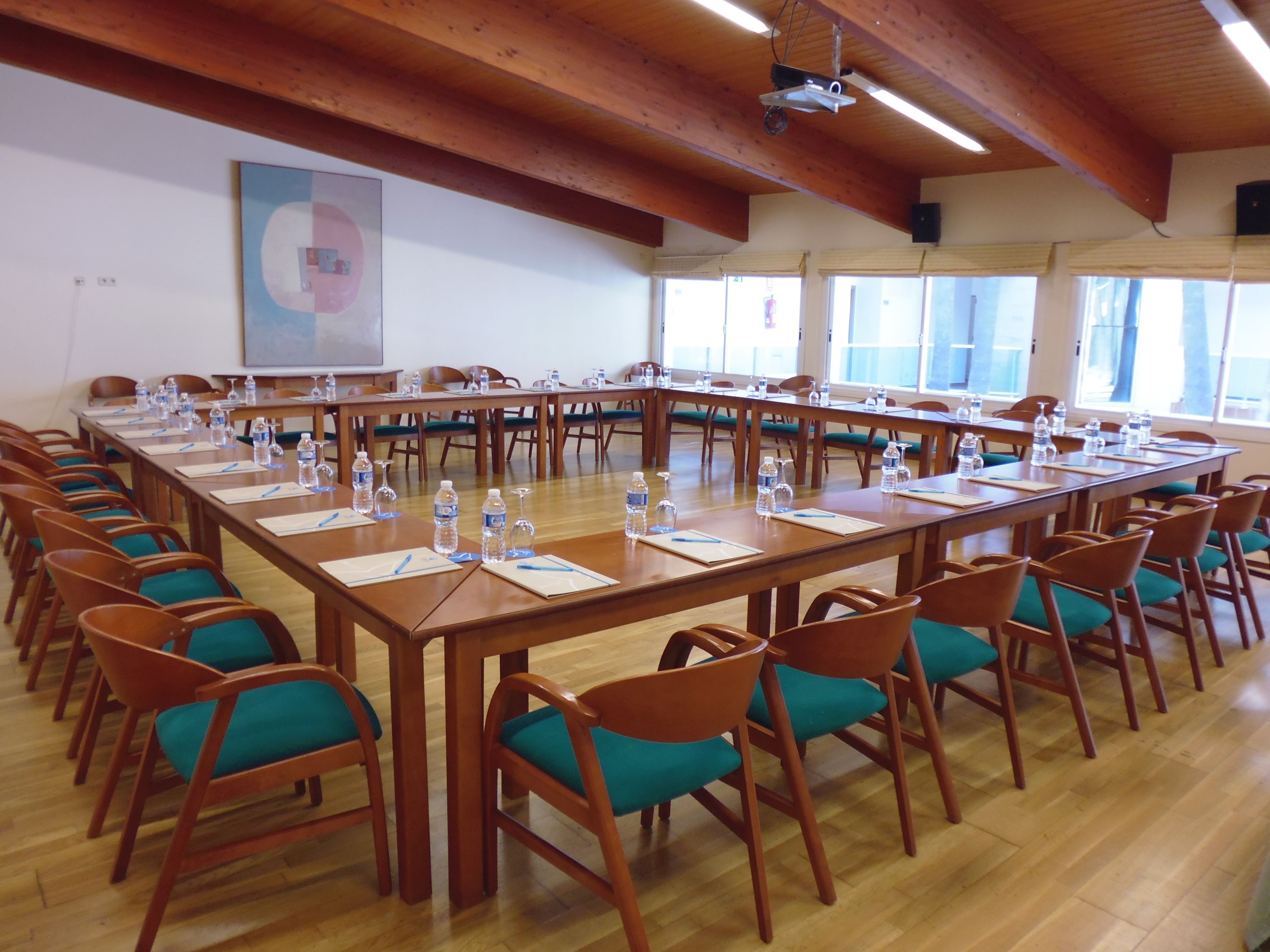 A conference room with a long table, chairs, water bottles, and a projector.