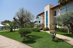 A modern building with a flat roof, a blue vertical stripe, and a paved walkway. - Grupotel Mallorca Mar (Son Servera)