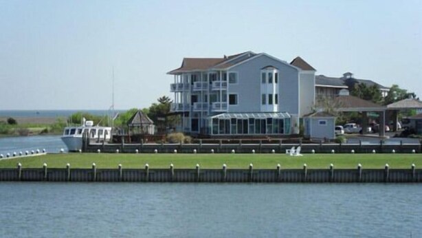 A large two-story house with a balcony, a covered patio, and a view of the water. - Island Resort (Chincoteague)