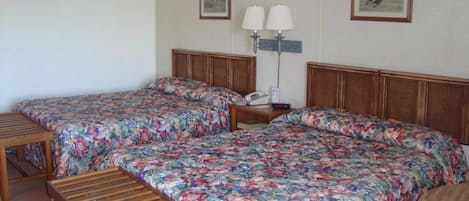 Een hotelkamer met twee eenpersoonsbedden, een houten bankje, een nachtkastje met een telefoon en twee wandlampen.