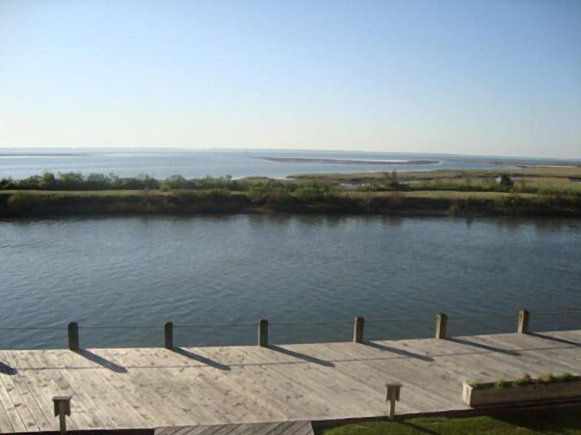 A wooden dock extending into calm water with a clear view of the distant shoreline.