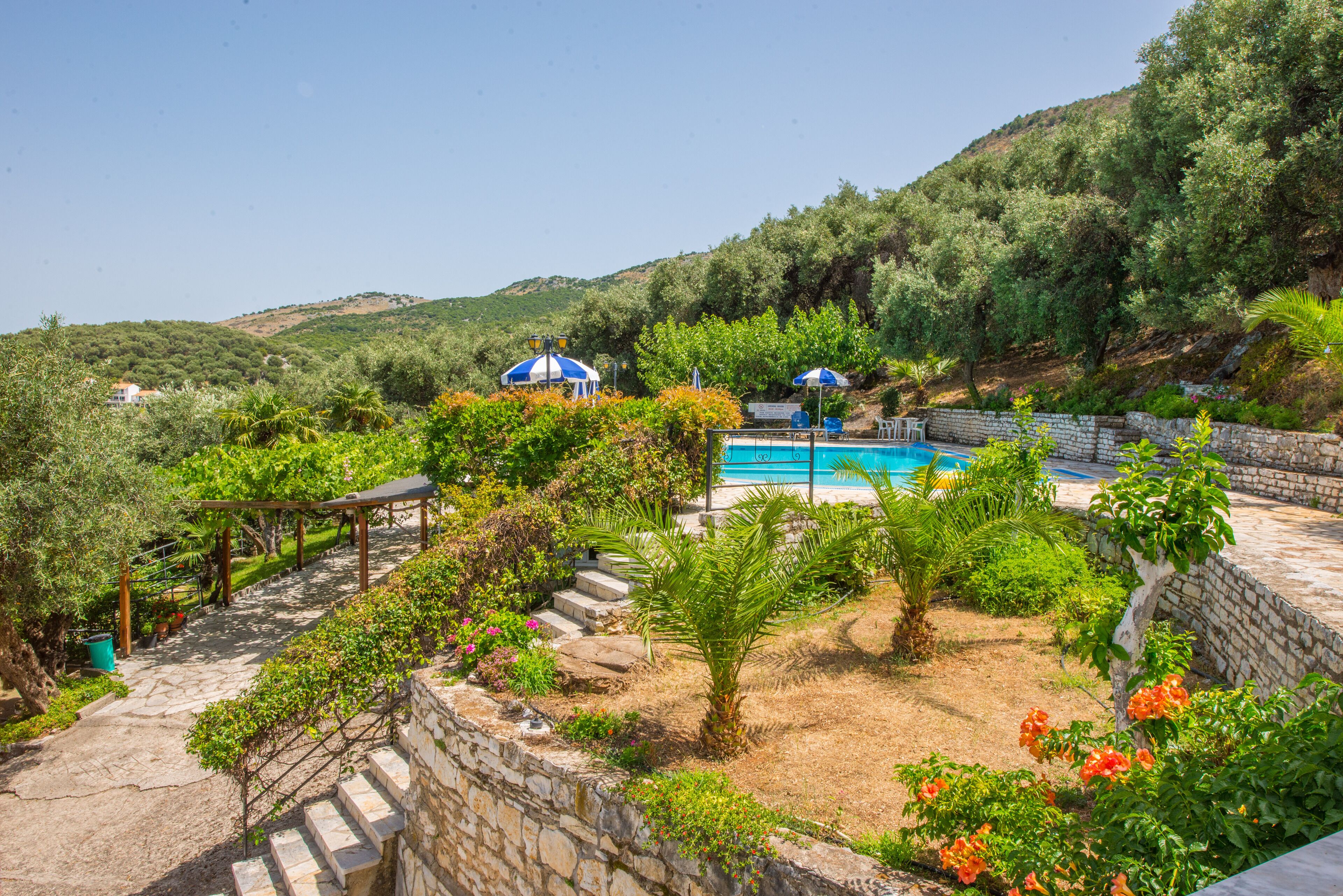 A pool area with a stone wall, steps, and a pergola.