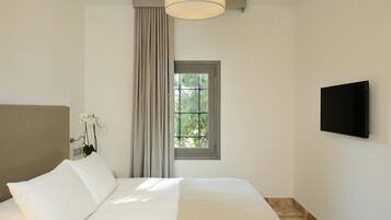 A bedroom with a bed, a window, a TV, and a plant.