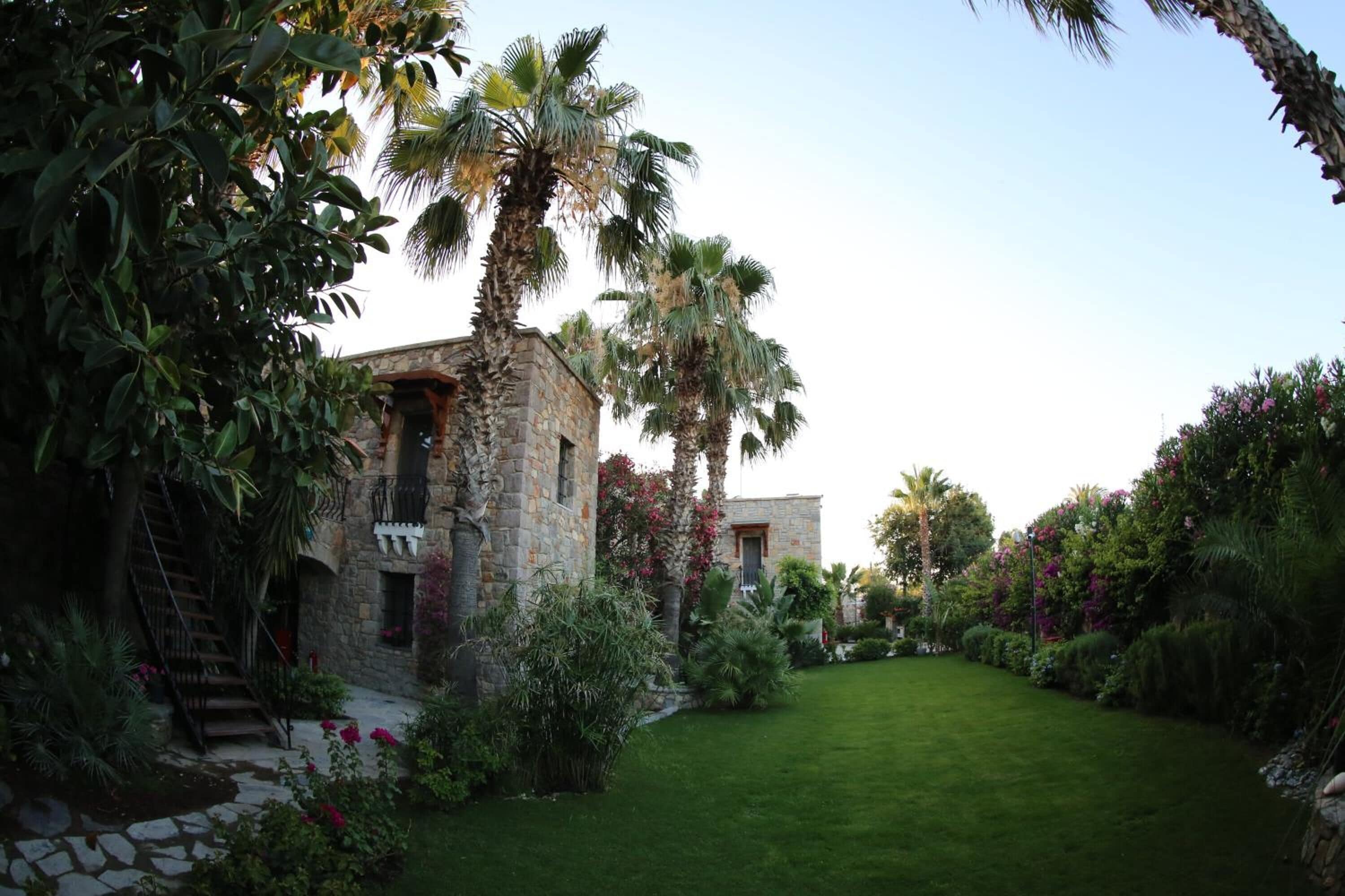 A stone building with a stone staircase, surrounded by lush greenery and a well-maintained lawn.