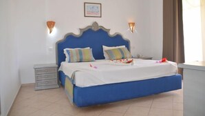 A bedroom with a blue bed, two pillows, a nightstand, and two wall-mounted lights. - Diar Yassine (Djerba Midun)