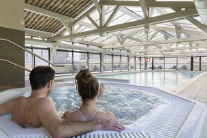 A couple relaxing in a hot tub with a view of the pool area and lounge chairs. - Garden & City Mont Ventoux - Malaucène (Malaucene)
