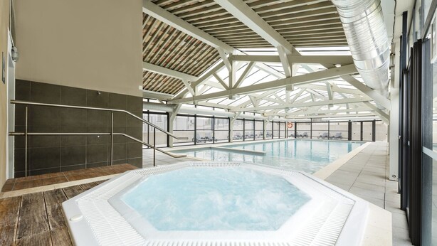 An indoor swimming pool with a hexagonal hot tub, a wooden deck, and a high ceiling with a skylight. - Garden & City Mont Ventoux - Malaucène (Malaucene)