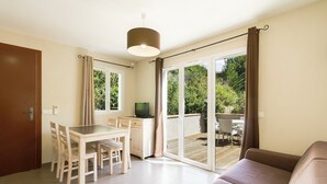 A room with a dining table, chairs, a sofa, a TV, and a sliding glass door leading to an outdoor area. - Garden & City Mont Ventoux - Malaucène (Malaucene)