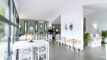 Un comedor moderno con mobiliario blanco, una barra y vistas amplias a través de grandes ventanales.