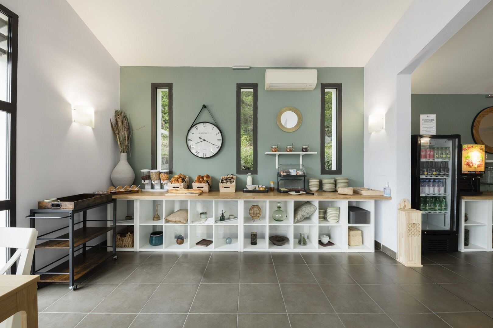 Un área de bar moderna con un reloj, estantes con varios objetos y un refrigerador.