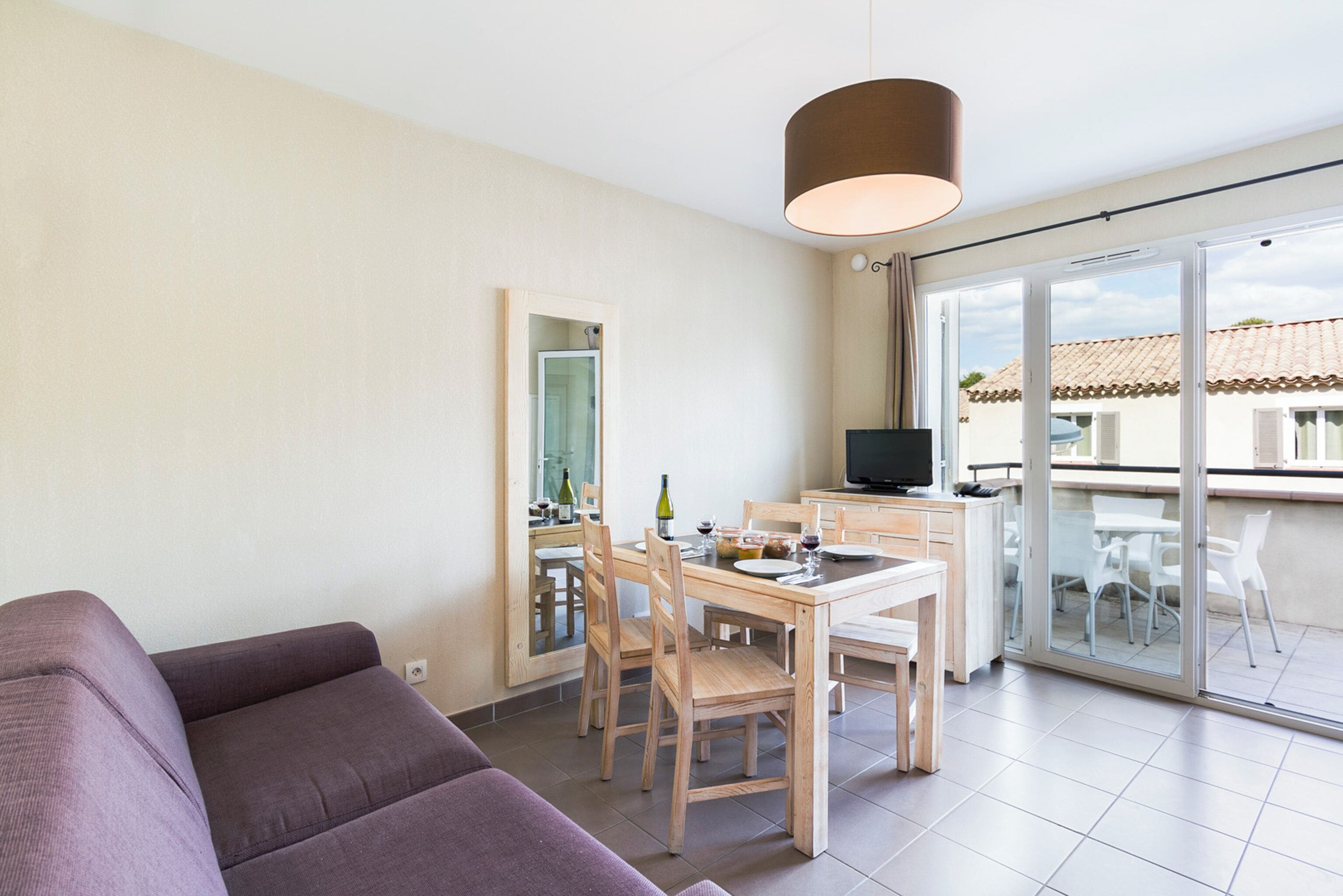 A modern living room with a sofa, dining table, chairs, and a TV.