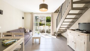 A modern living room with a sofa, coffee table, and TV stand. There is a staircase leading to an upper level. - Garden & City Mont Ventoux - Malaucène (Malaucene)