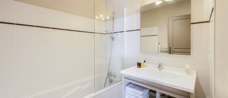 A modern bathroom with a glass-enclosed shower, a white vanity with a mirror, and neatly folded towels.