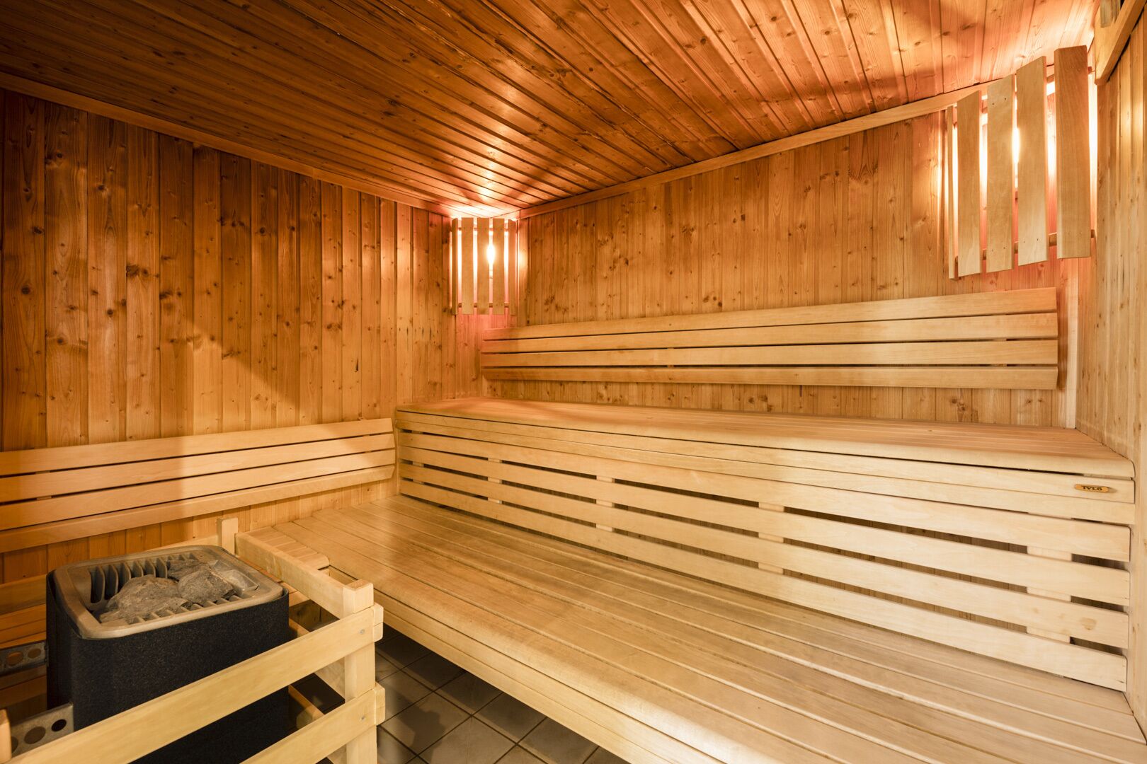 Una sauna de madera con bancos y un calentador de piedra.
