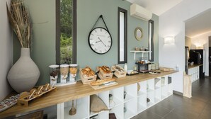 A breakfast bar with various food items and a clock on the wall. - Garden & City Mont Ventoux - Malaucène (Malaucene)