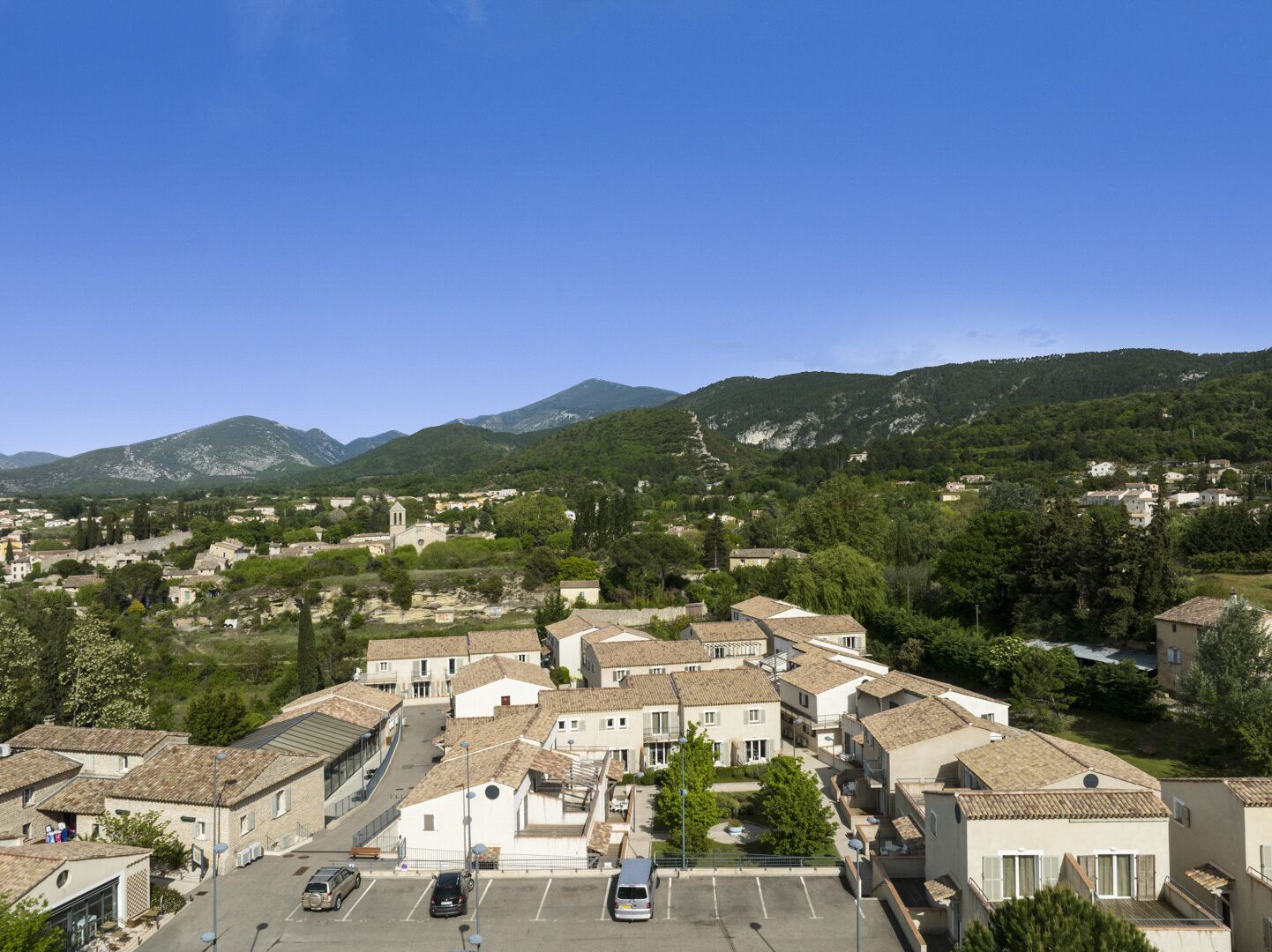 Un quartier résidentiel avec des maisons à étages, une église et des montagnes en arrière-plan.