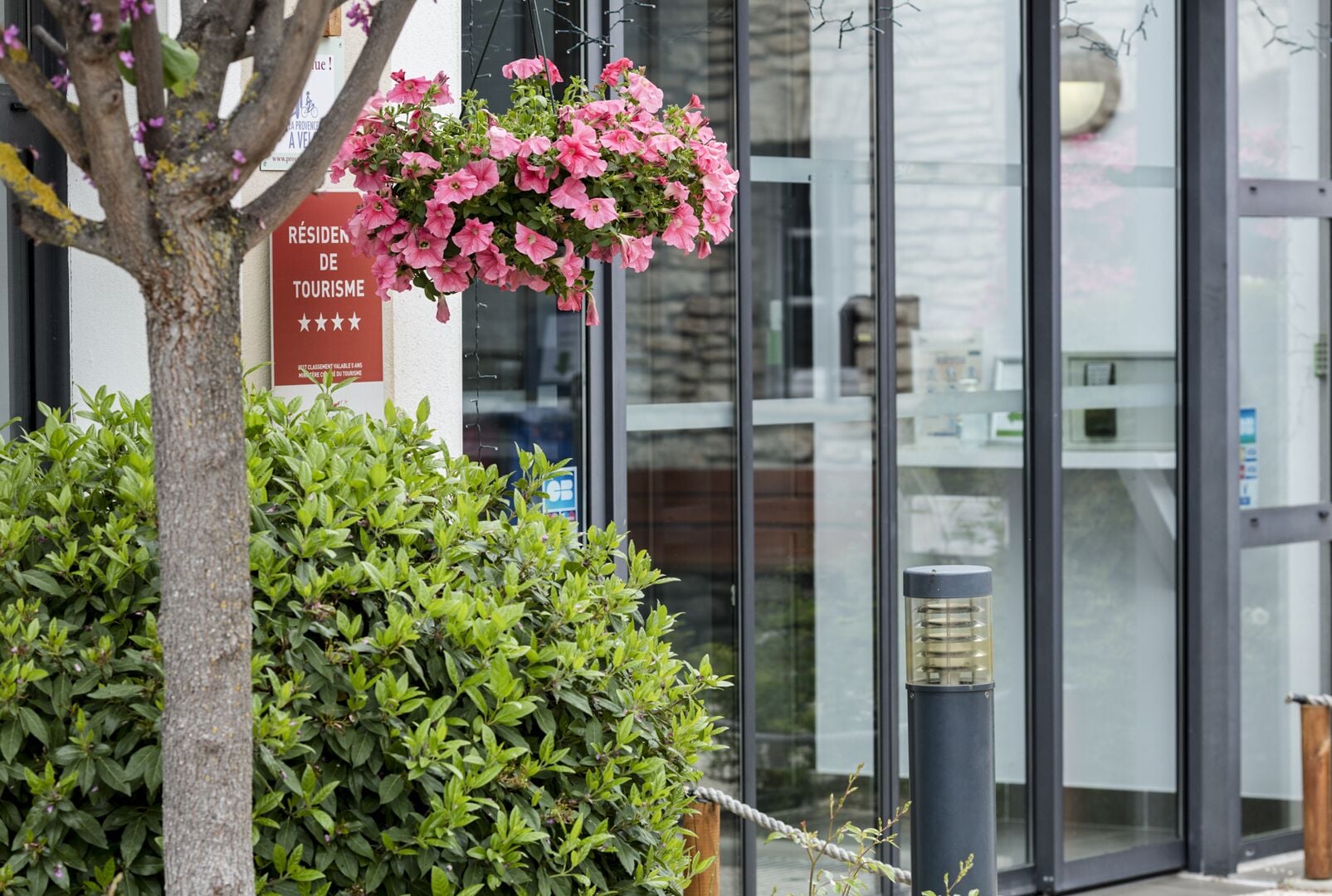A hotel entrance with a sign indicating it is a residence hotel, a potted plant, and a hanging flower arrangement.