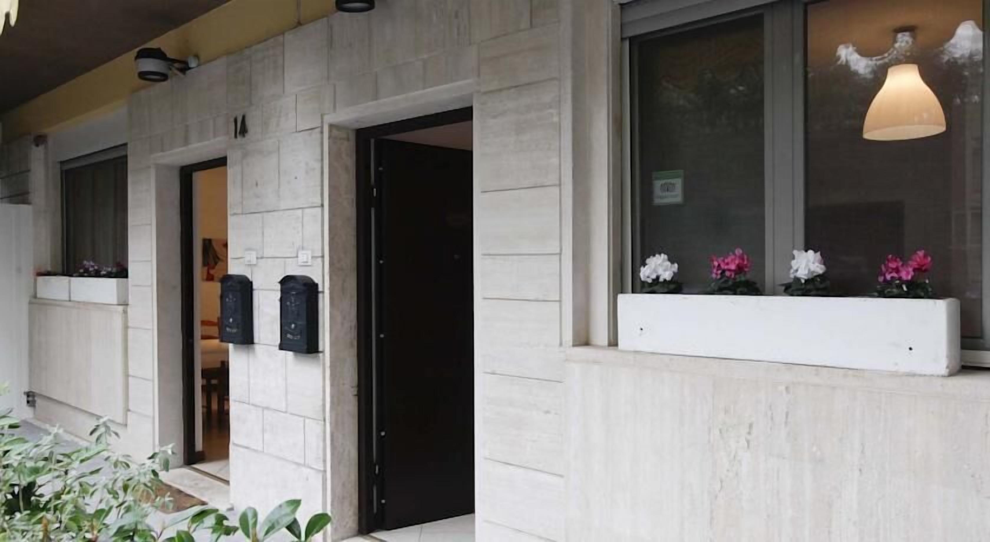 Fachada de edificio con diseño moderno, que presenta un gran ventanal con lámpara colgante y jardineras.