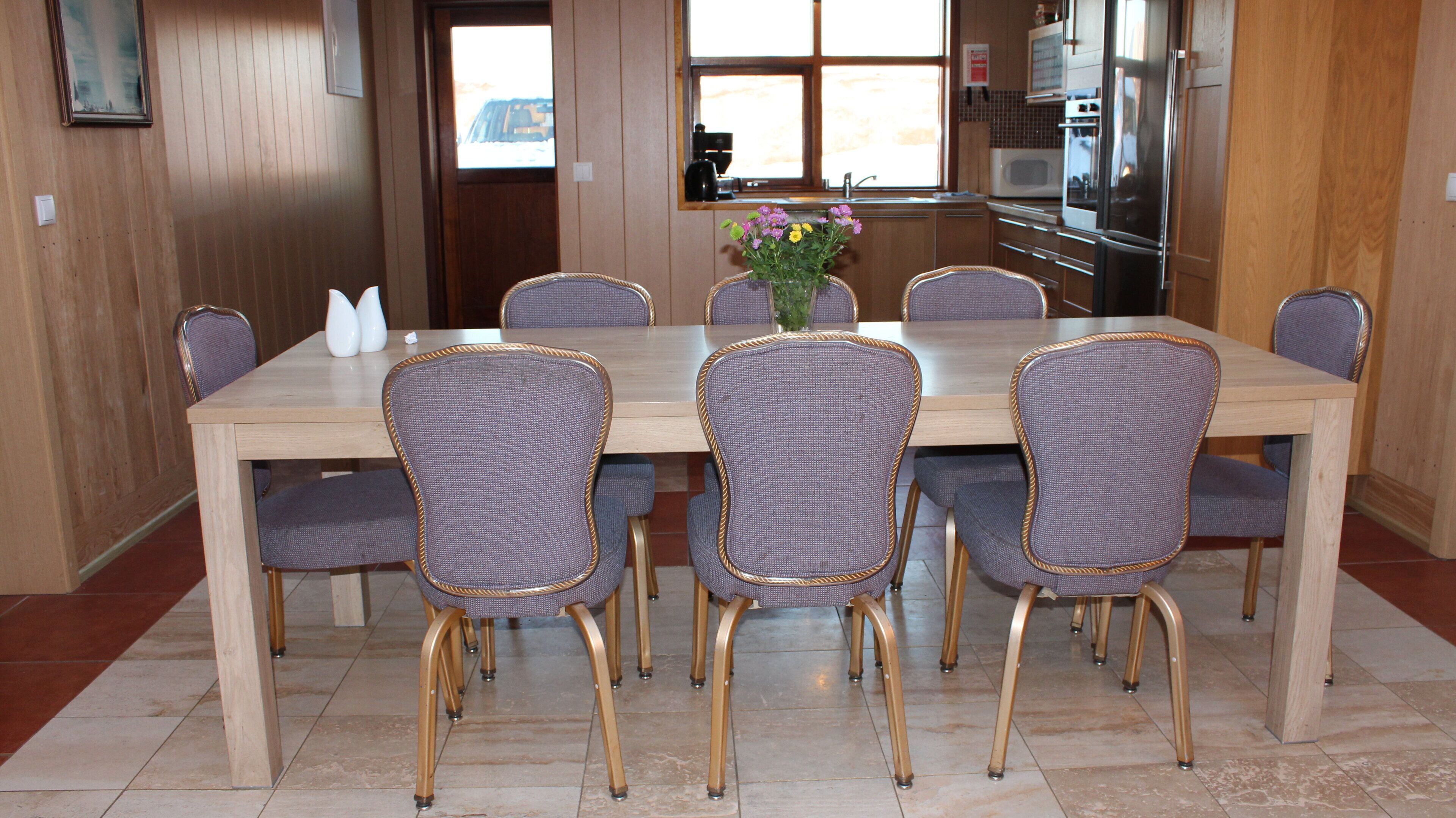 A dining area with a wooden table and six wicker chairs.