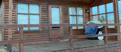 Eine Holzhütte mit Veranda, großen Fenstern und einer Satellitenschüssel.