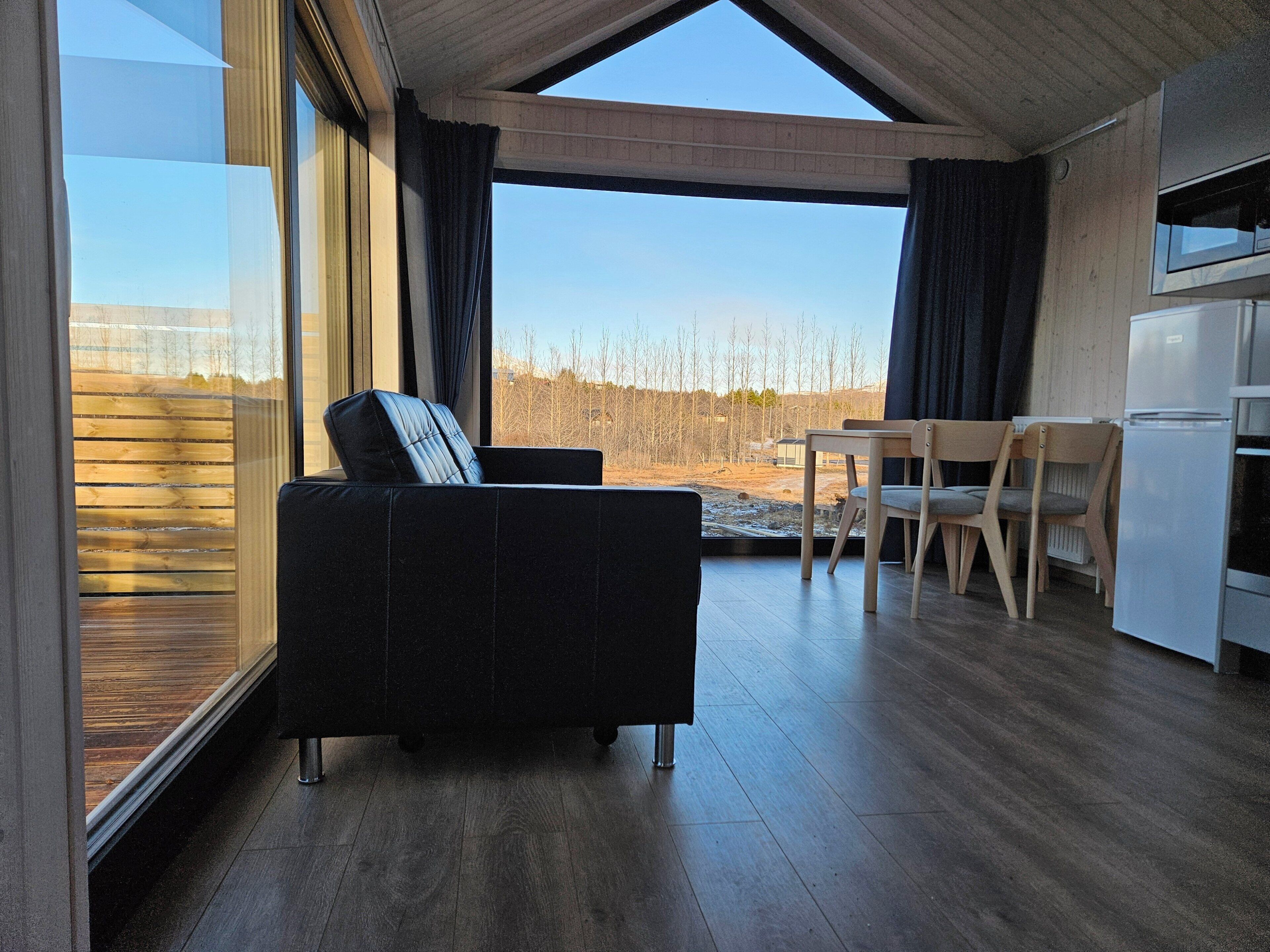 A modern interior with a sofa, dining table, chairs, and a kitchen area.
