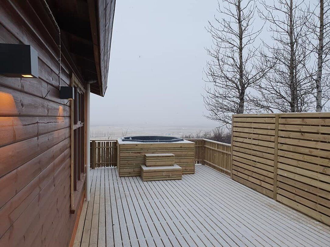 Una terraza de madera con un jacuzzi y escalones que conducen a otra zona de terraza.