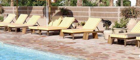 A pool area with lounge chairs and umbrellas.