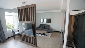 A modern living room with a large flat-screen TV, a sofa, a coffee table, and a fireplace. - Urban by CityBlue, Kigali, Rwanda (Kigali)