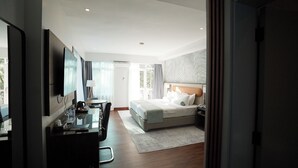 A hotel room with a bed, a desk, a chair, a TV, and a view of the outdoors. - Urban by CityBlue, Kigali, Rwanda (Kigali)