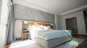 Ein modernes Hotelzimmer mit einem großen Bett, einem Nachttisch, einer Wandlampe und einer Tür.