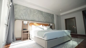 Une chambre d’hôtel moderne avec un grand lit, une table de chevet, une lampe fixée au mur et une porte.