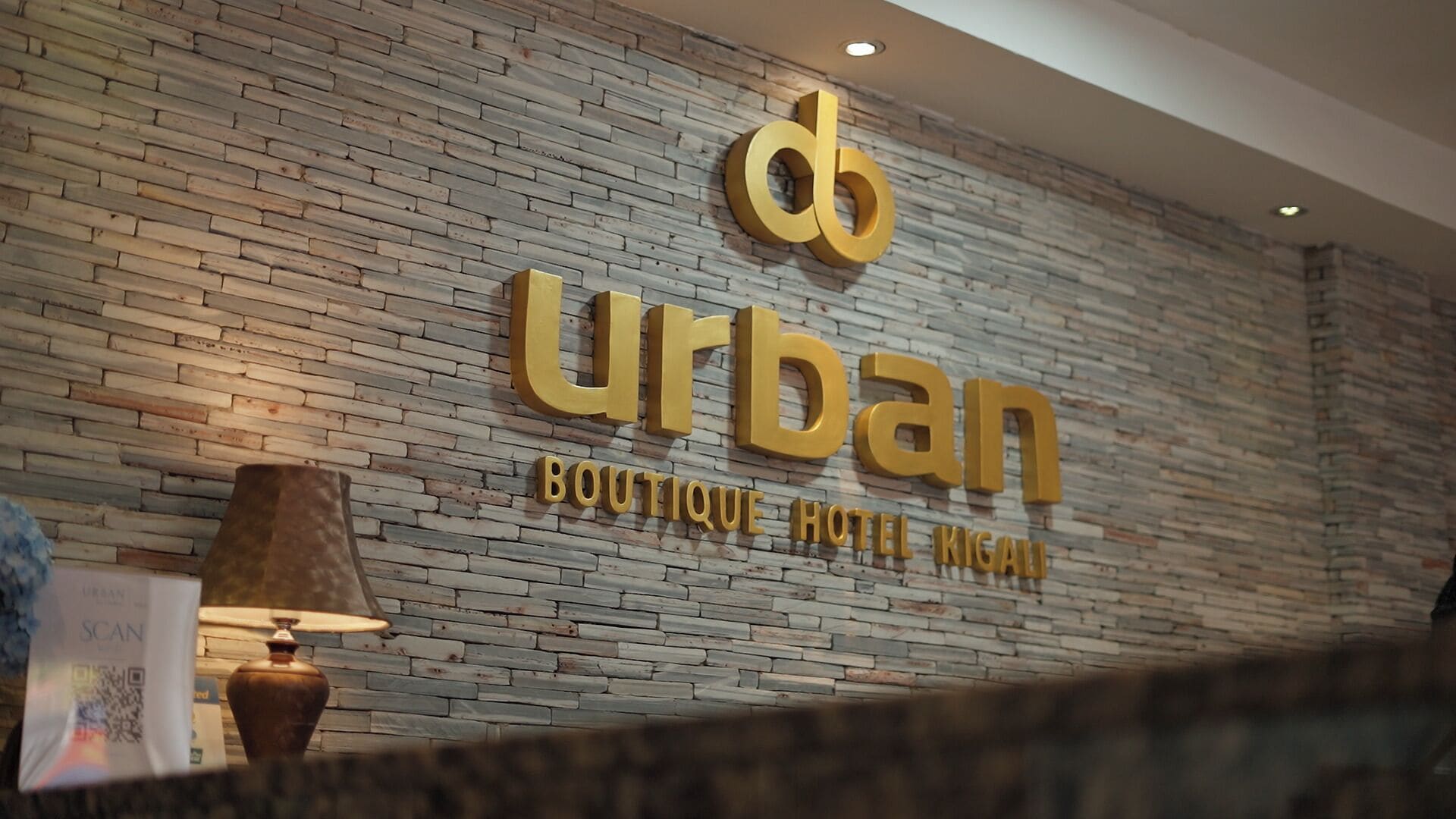 A brick wall with the words 'urban boutique hotel kigali' in gold lettering.