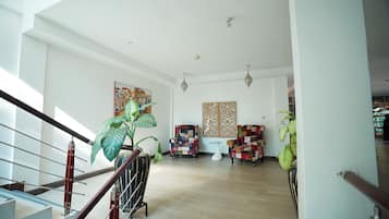 Amplia sala de estar con escalera, una planta grande, dos sillones y un panel decorativo en la pared.