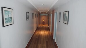 A hallway with framed pictures on the walls, a wooden floor, and a light fixture at the end. - Urban by CityBlue, Kigali, Rwanda (Kigali)