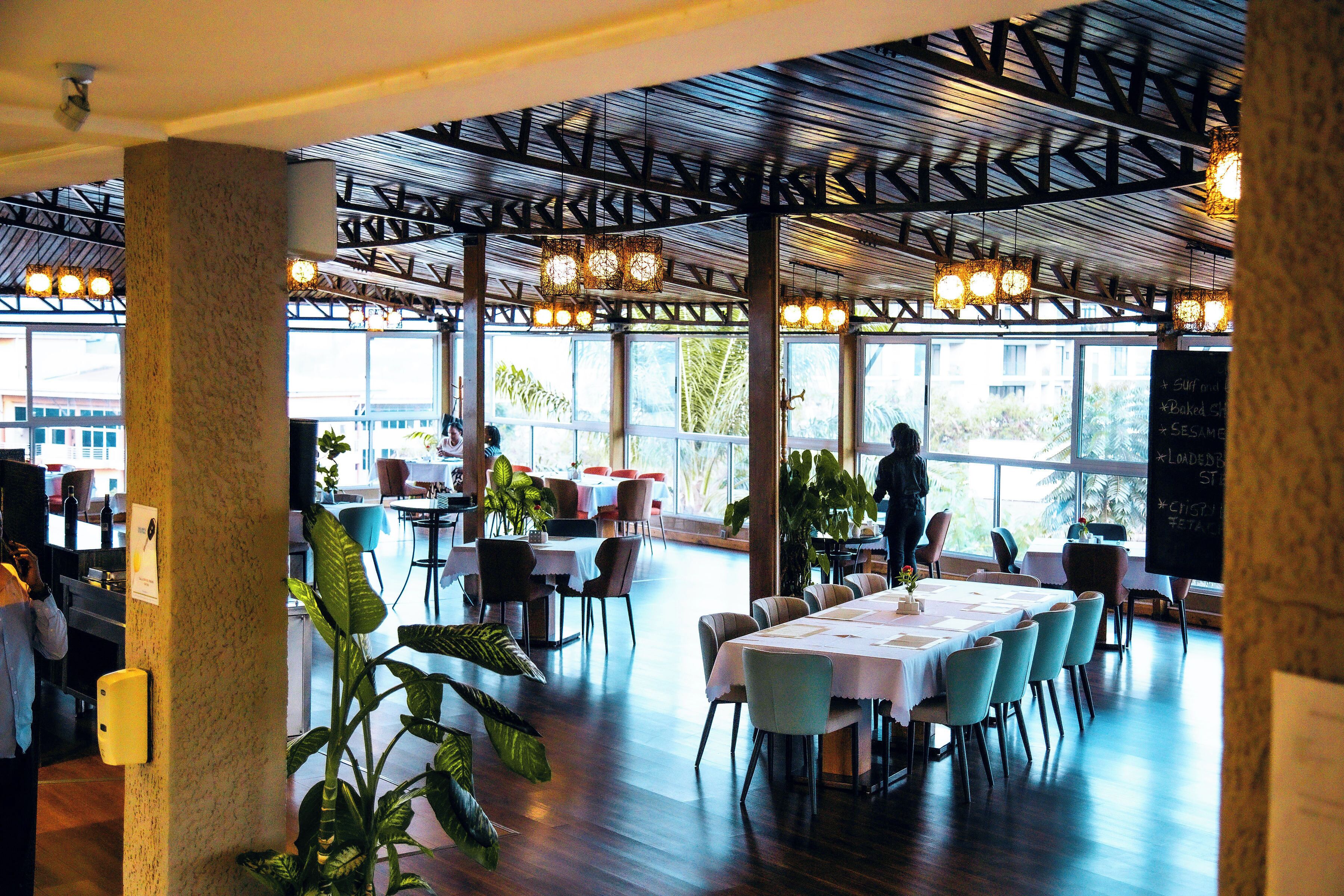 An indoor dining area with tables, chairs, and a high ceiling with exposed beams.