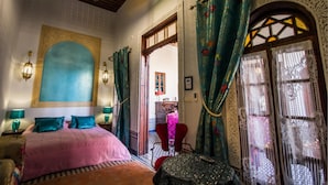 Un dormitorio con una cama grande, techo de madera y vista a otra habitación con una silla roja.