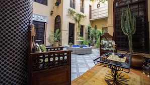 Un patio con una fuente, plantas en macetas y un cactus.