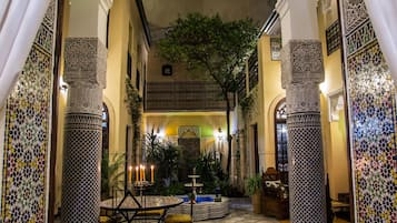 An indoor courtyard with tiled flooring, ornate columns, and a central fountain.