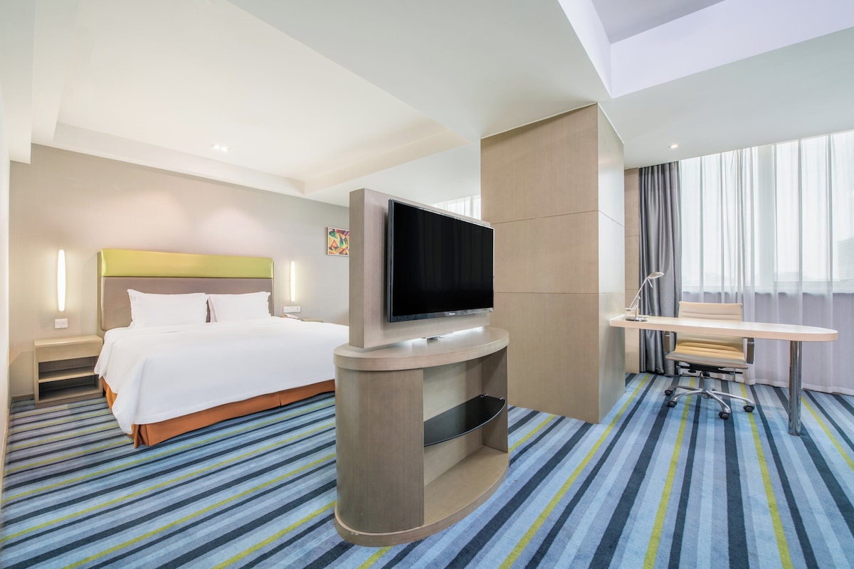 Una habitación de hotel con cama, televisión de pantalla plana, escritorio y silla.