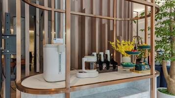 A modern kitchen with a marble countertop, a coffee machine, and a decorative plant arrangement.