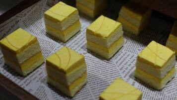 A display of layered yellow cakes on a newspaper.