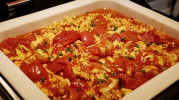 A white rectangular baking dish filled with scrambled eggs, tomatoes, and green onions.