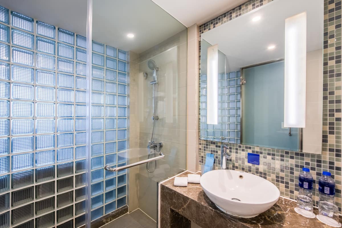 A modern bathroom with a glass shower enclosure, a marble sink, and a large mirror.