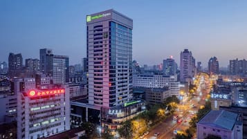A high-rise hotel with multiple floors, a prominent sign for Holiday Inn Express, and a busy street with vehicles and illuminated buildings in the background.