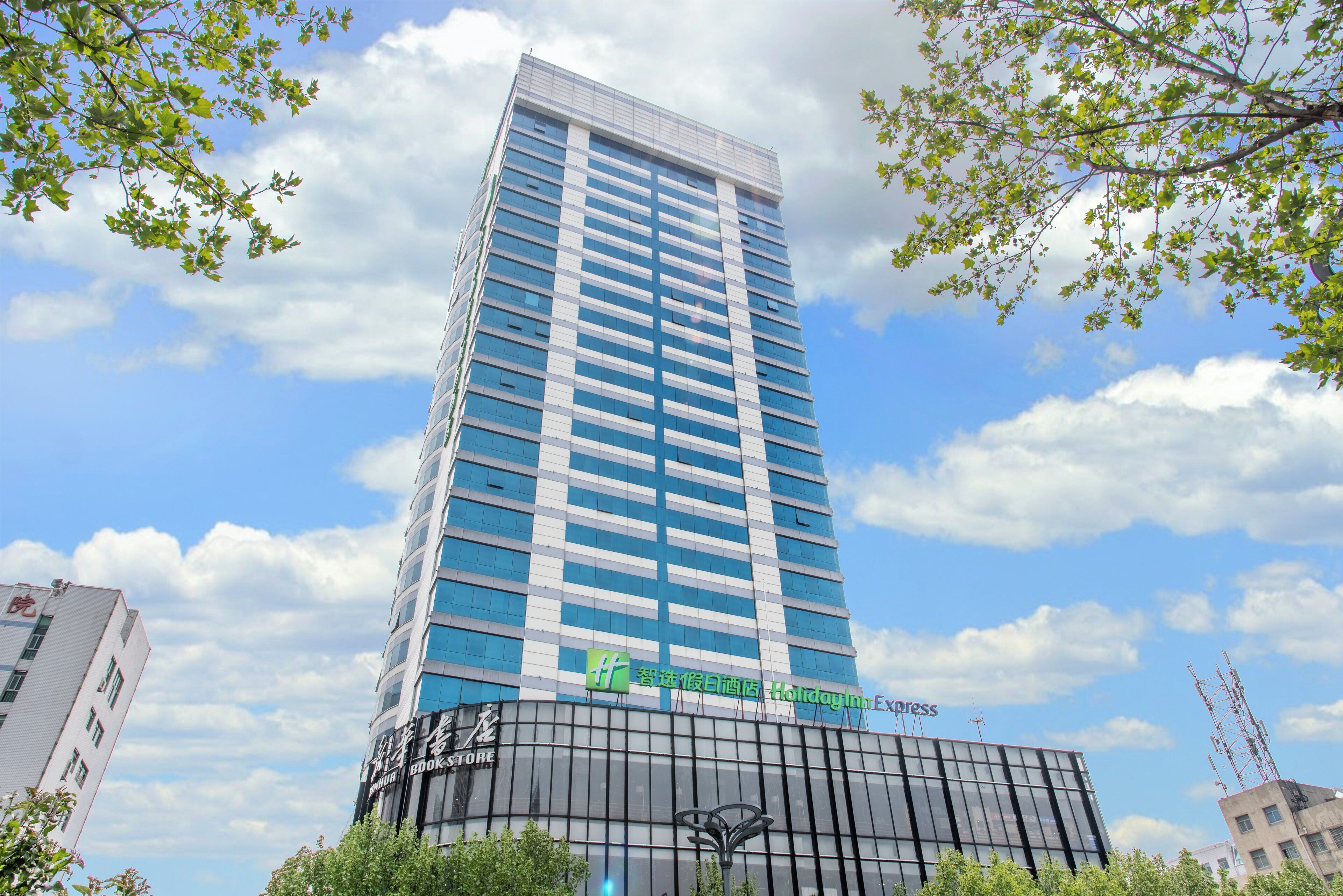 A multi-story building with a glass facade, a visible signage for a Holiday Inn Express, and a lower level with a dark facade.